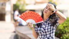 Person with fan wiping their brow